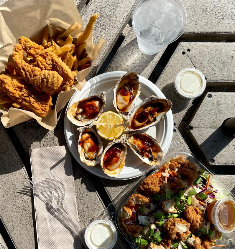 Fried chicken, BBQ oysters, and salad on the patio table